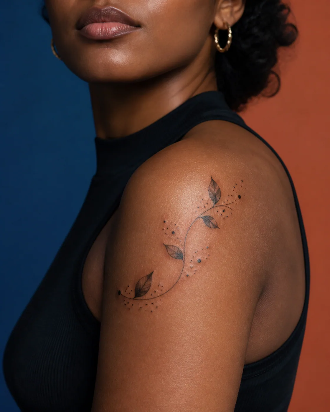 Black and Gray tattoo of scattered dots and leaves linked by one curved line on the shoulder cap