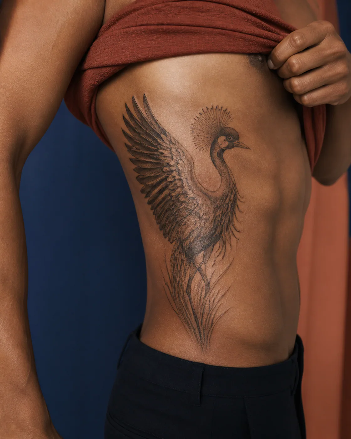 Dotwork tattoo of a crowned crane opening one wing on the side ribs