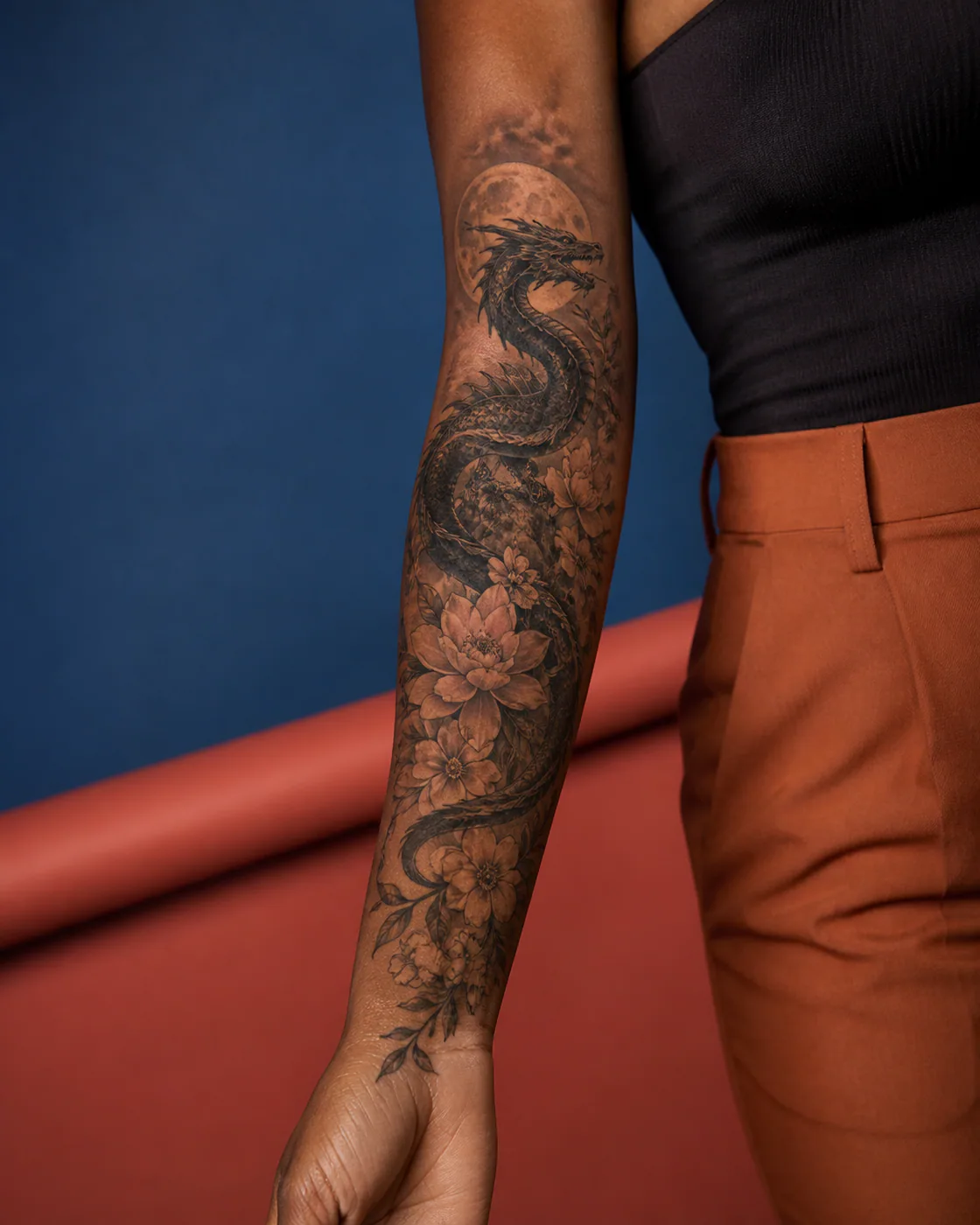 Floral tattoo of a sea serpent coiling around a moonlit rock on the forearm