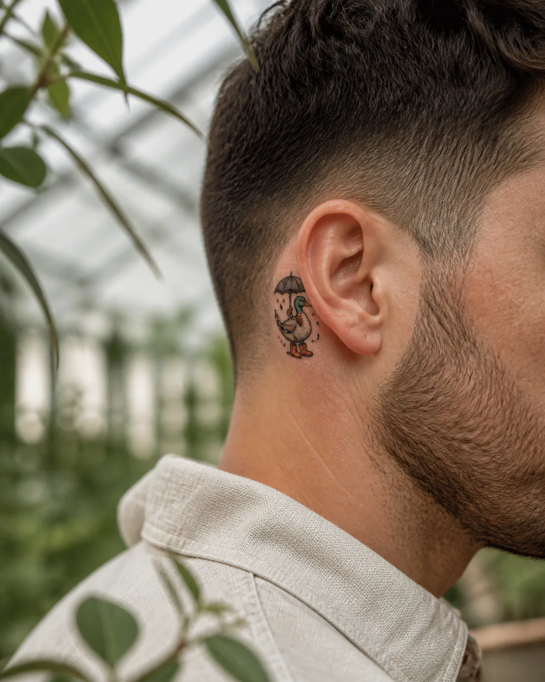 Neo-Traditional tattoo of a proud duck walking through rain in tiny boots on the behind the ear