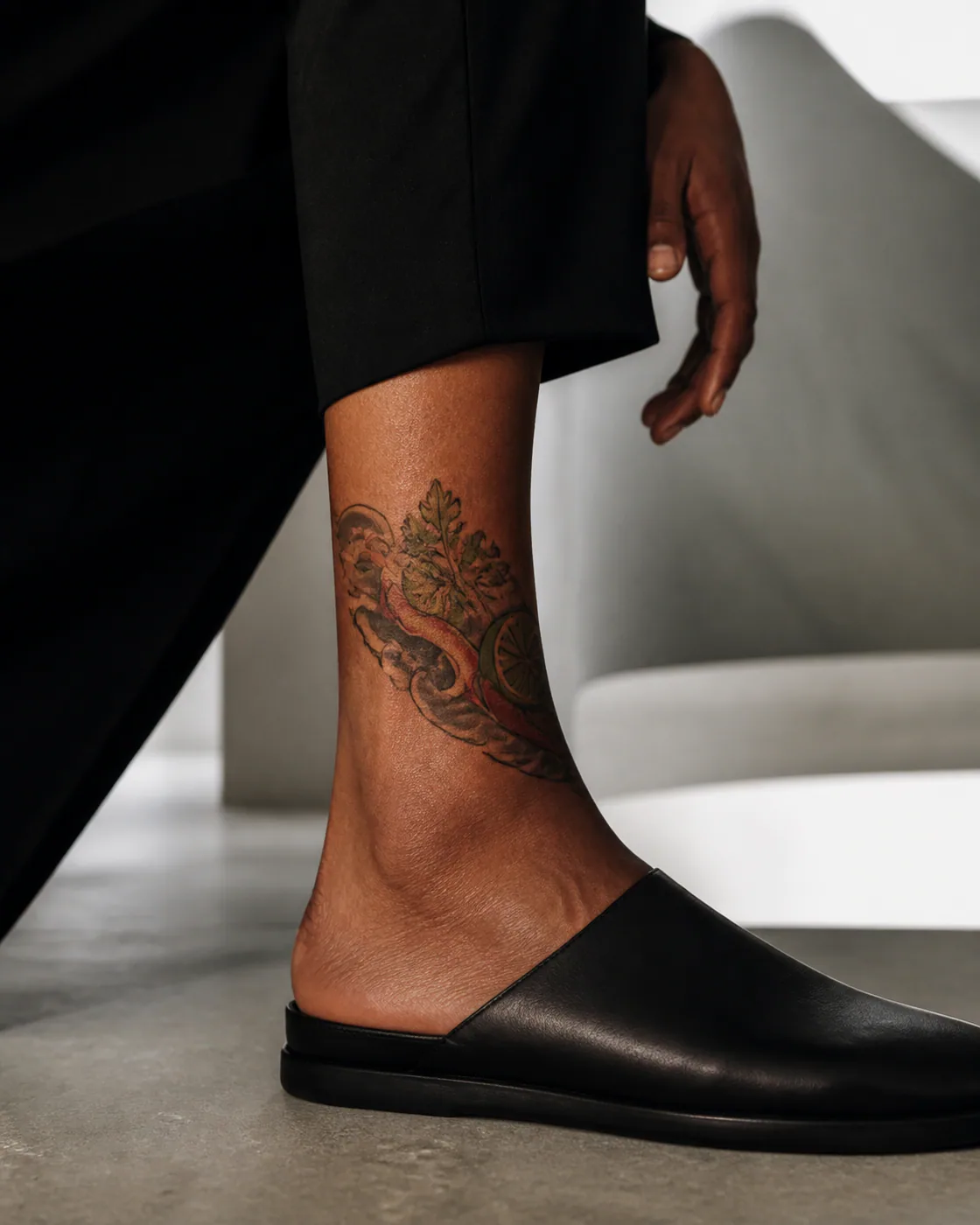 Japanese tattoo of chili, lime, and coriander arranged in a sharp diagonal with a three-part family motif on the ankle