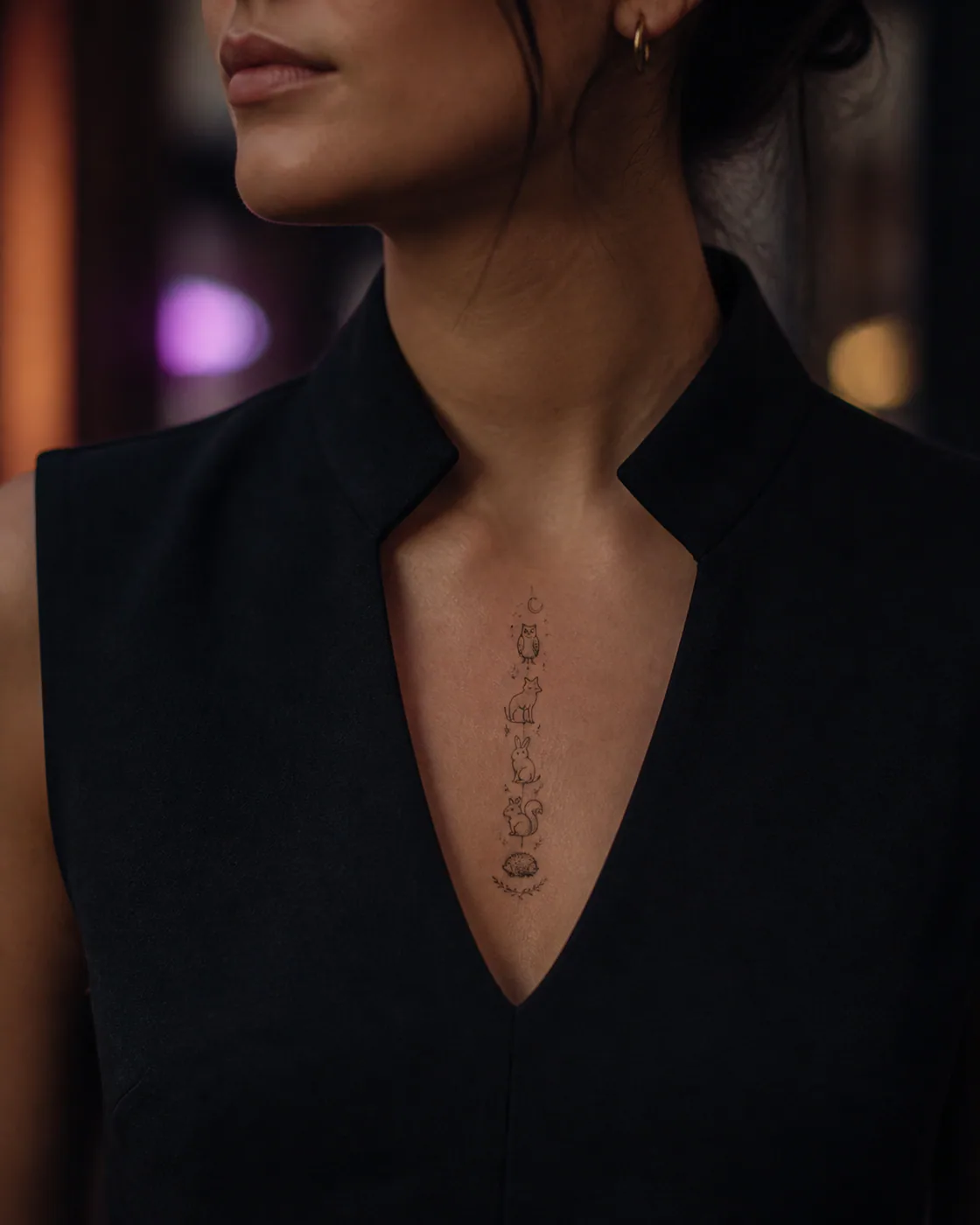 Minimalist tattoo of a playful parade of miniature woodland creatures on the sternum