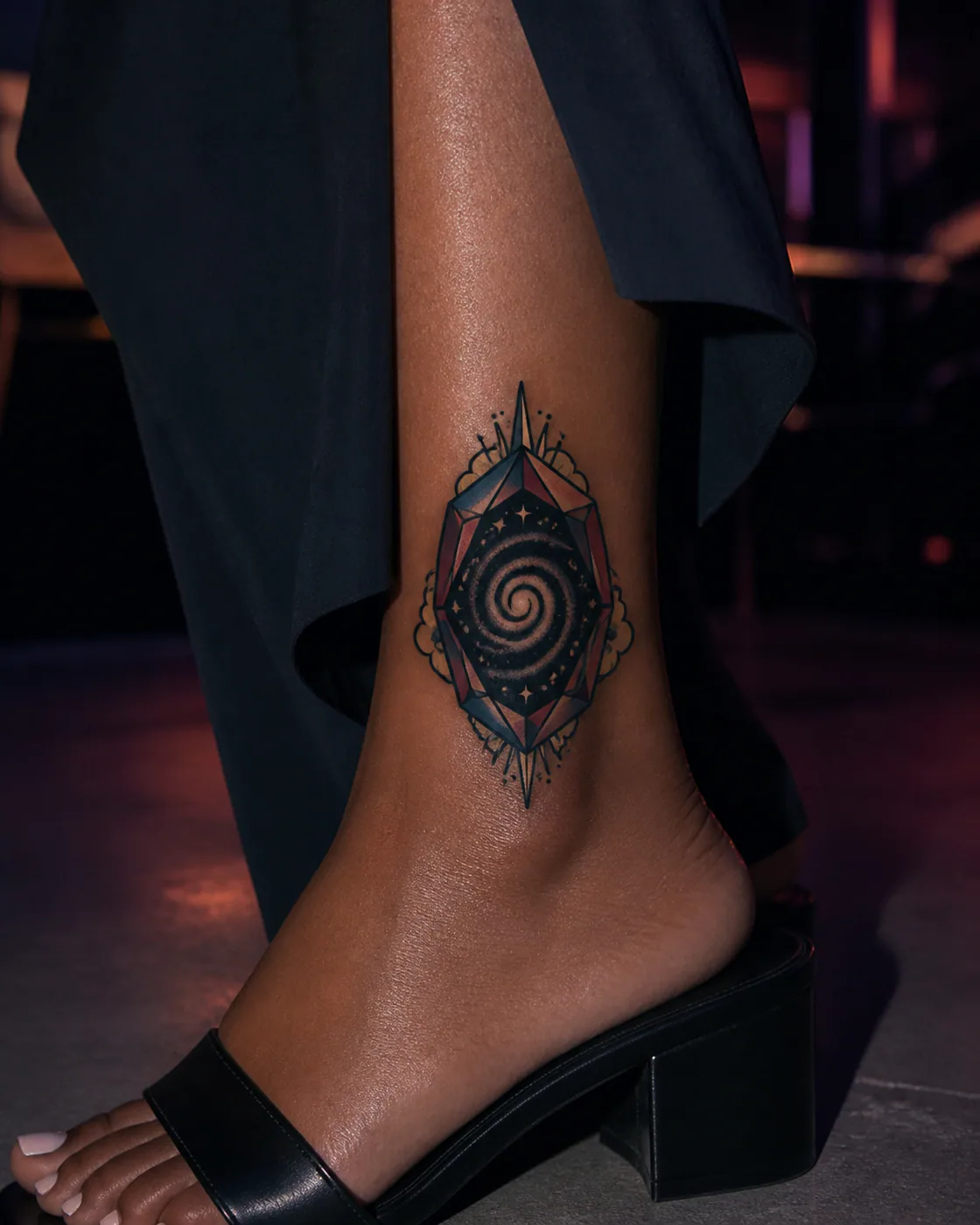 American Traditional tattoo of a spiral galaxy opening inside a faceted portal on the ankle