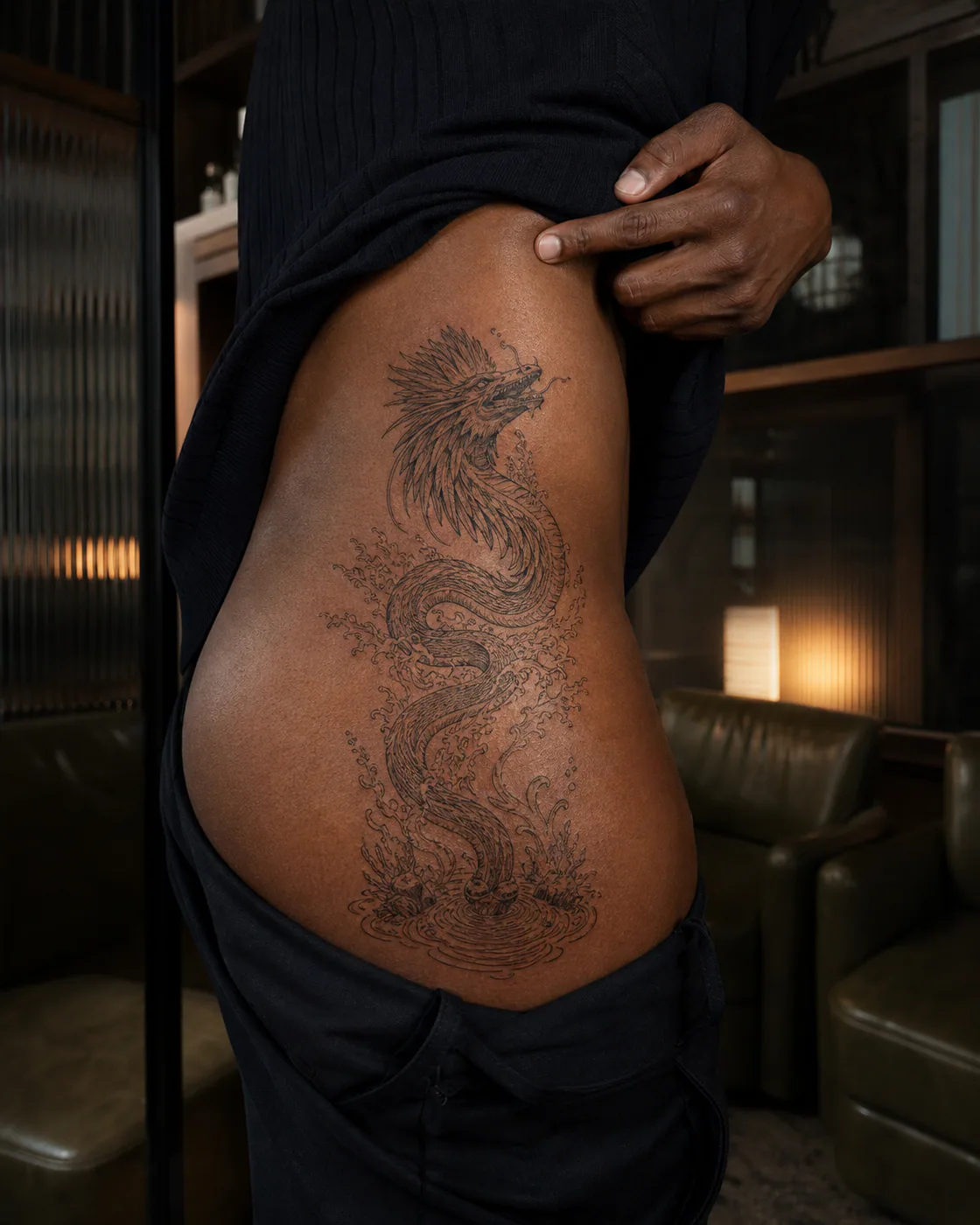 Fine Line tattoo of a feathered serpent rising through a freshwater spring on the hip