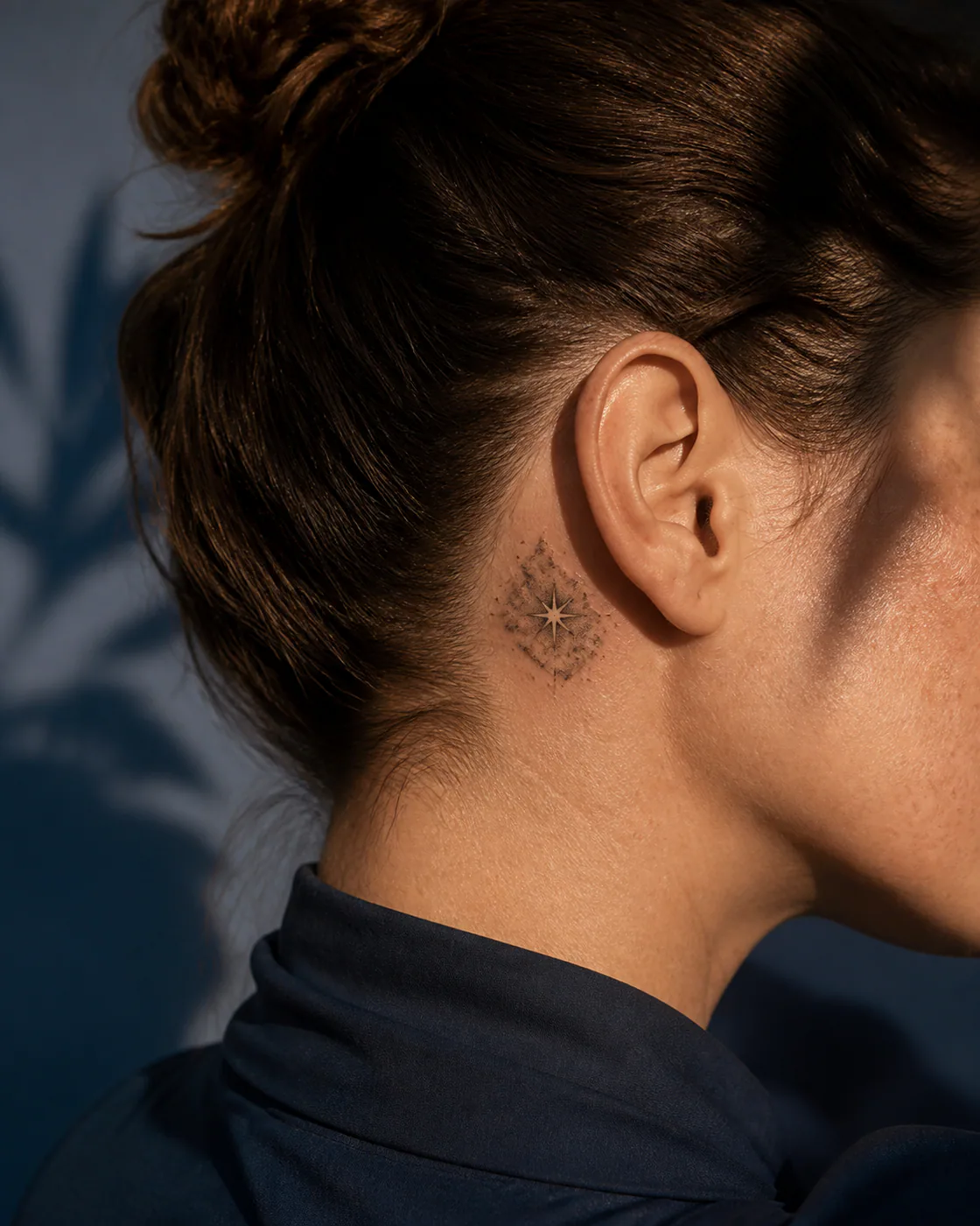 Minimalist tattoo of a newborn star glowing within layered clouds of dust on the behind the ear