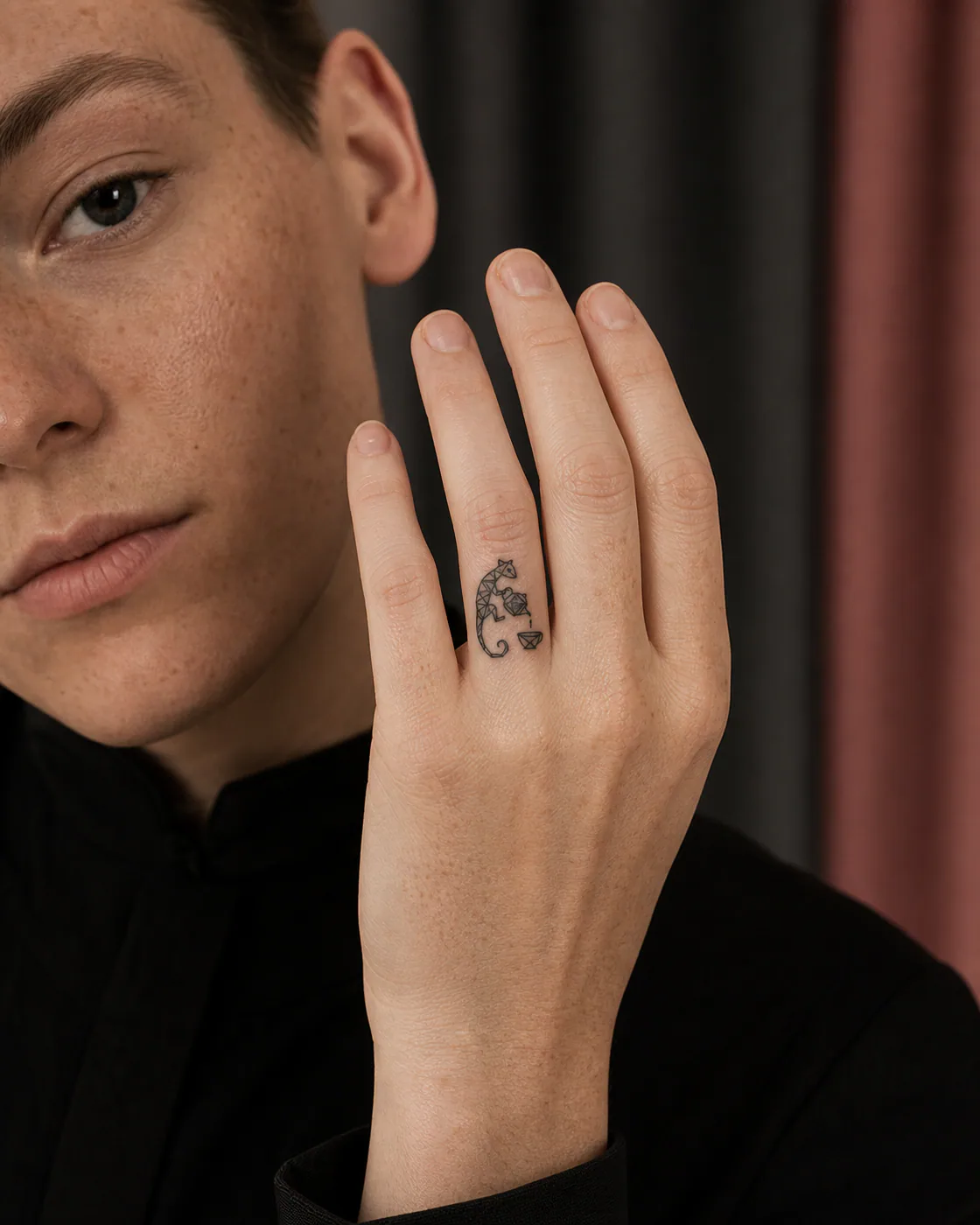 Geometric tattoo of a gecko serving tea from a tiny unmarked kettle with a three-part family motif on the finger