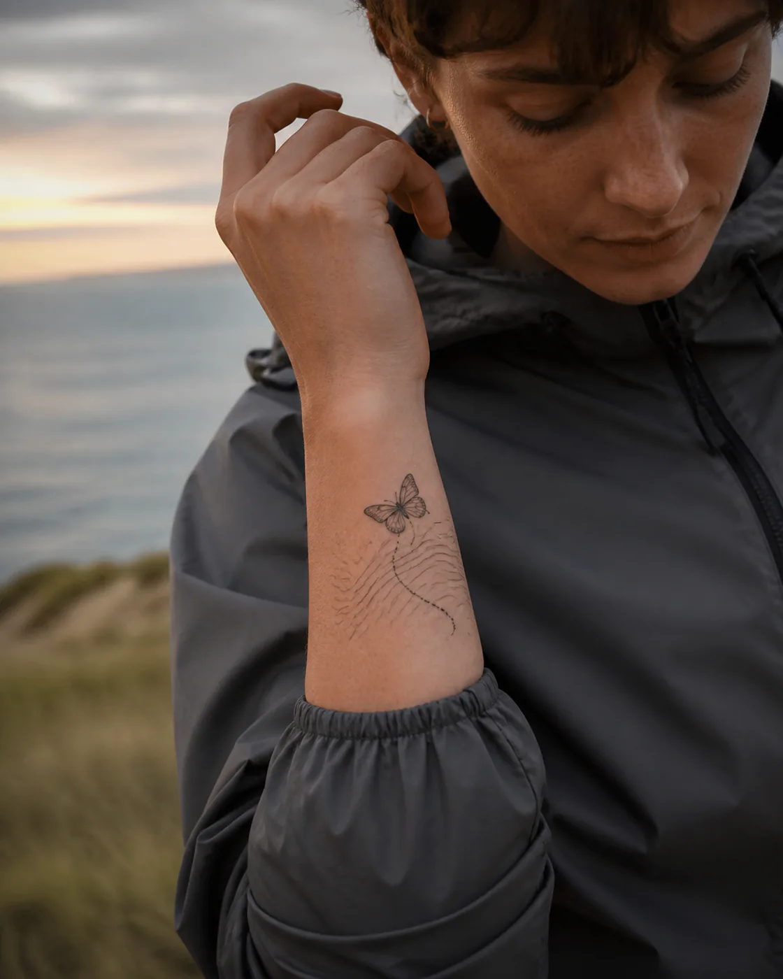 Minimalist tattoo of a migrating butterfly following layered topographic contours featuring an integrated butterfly on the wrist