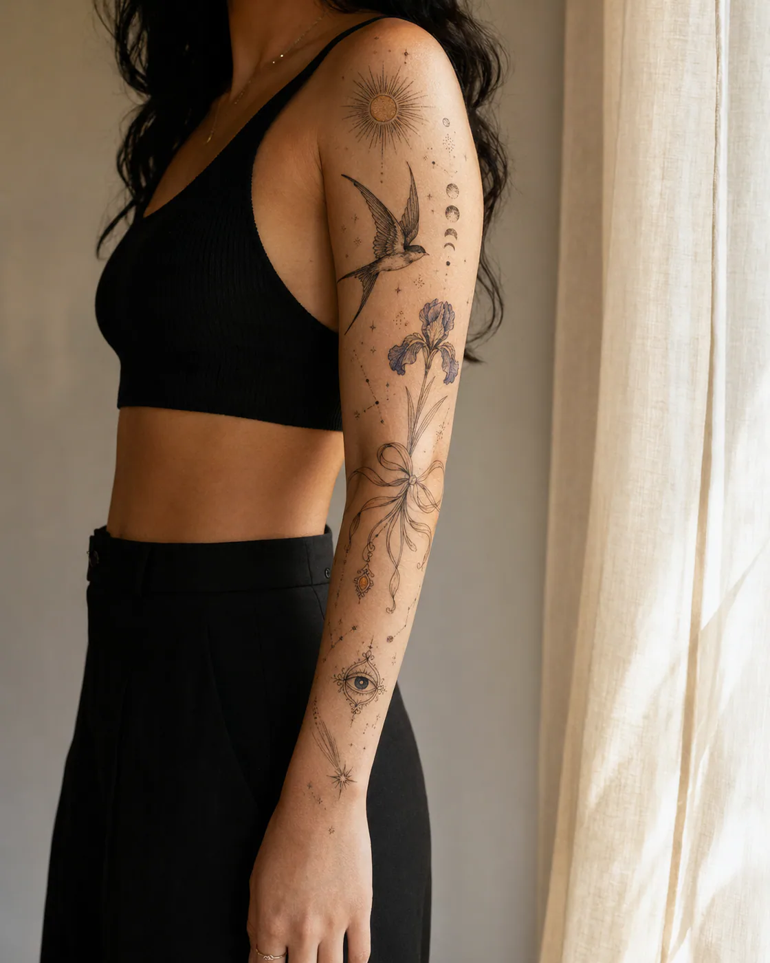 Fine-line patchwork sleeve tattoo showing a flying bird, sun, moon, orbital lines, constellation dots, and an ornamental ribbon on olive skin